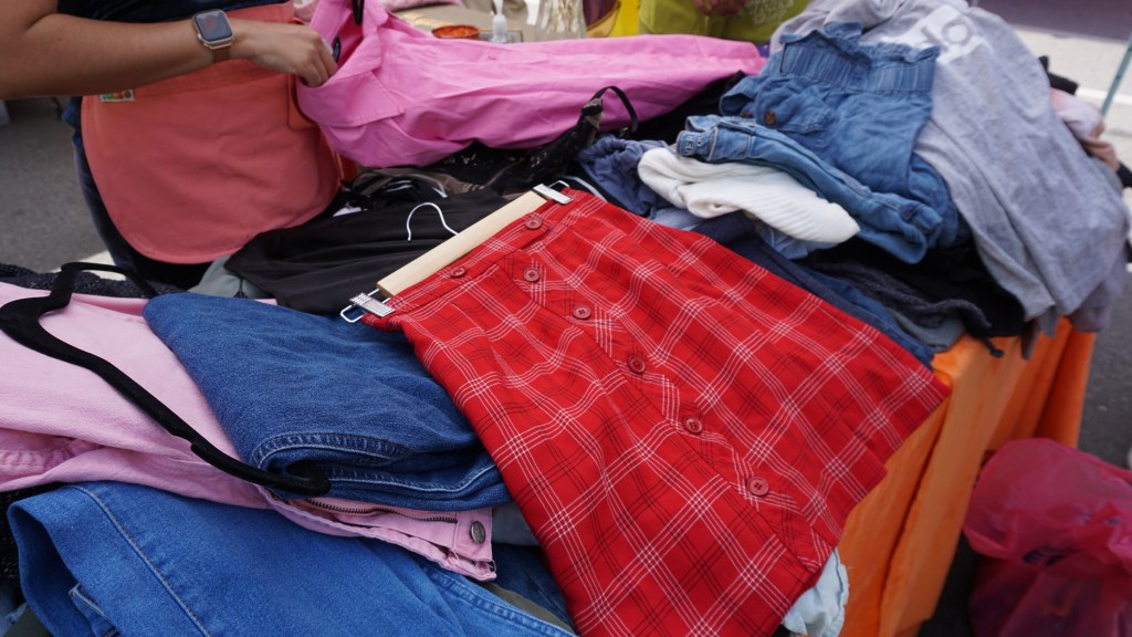 A red plaid skirt laid on top of a pile of clothing donations.